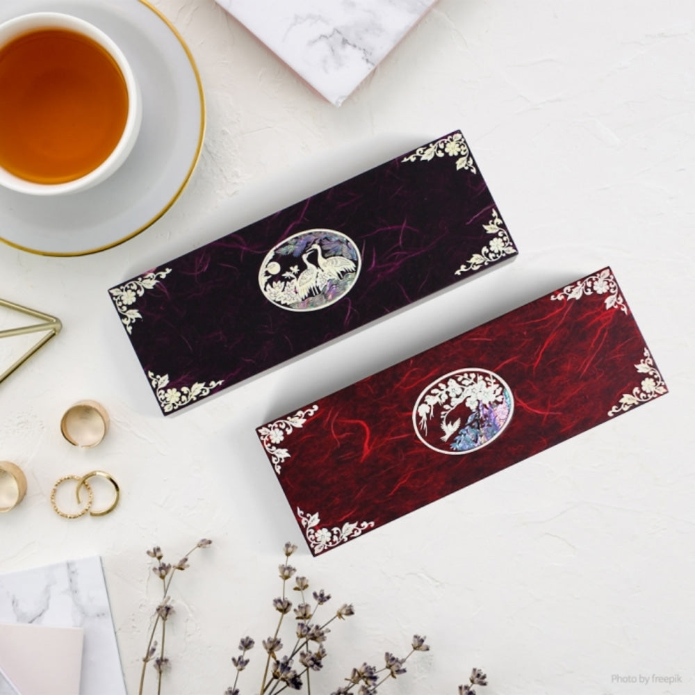Two long Korean lacquer pen cases in black and red, each with an oval mother-of-pearl medallion of a crane among pine at the centre and shell scrollwork in the corners