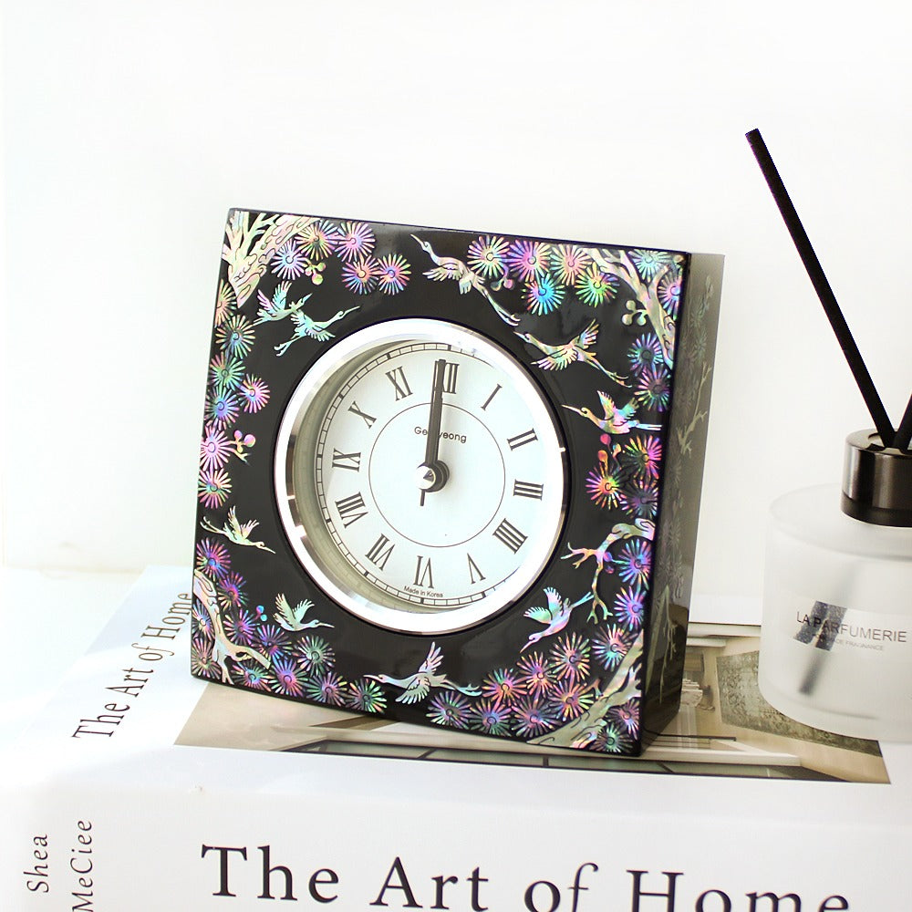 Square black lacquer Korean desk clock with a roman-numeral dial, cranes in flight and small blossoms inlaid in coloured mother-of-pearl around the face