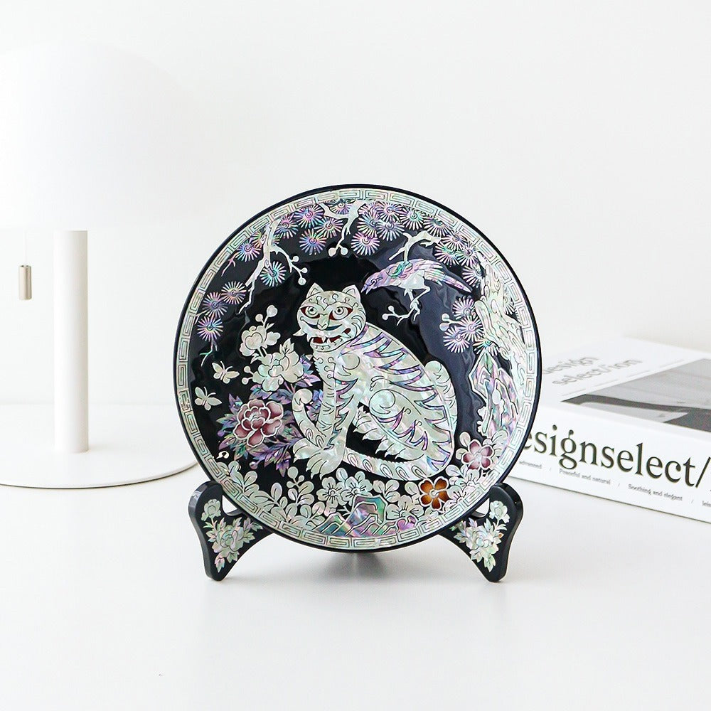 Round black lacquer Korean ornament tray on a stand, a grinning striped tiger beneath a magpie in a pine tree with peonies, inlaid in mother-of-pearl inside a fret border