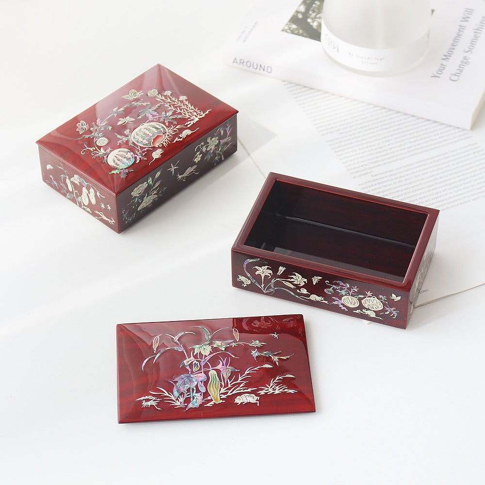 Red lacquer Korean stacked box set with the lid set aside, melon vines, lilies, butterflies and insects inlaid in mother-of-pearl across the lid and sides